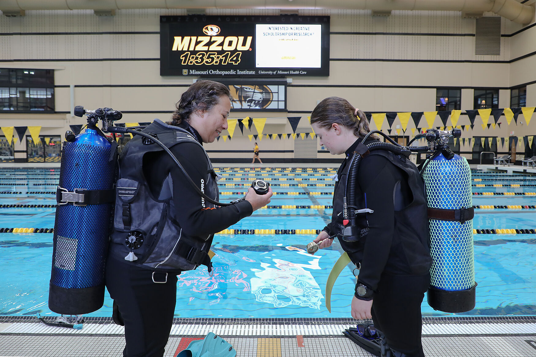 Diving partners Tanya Haeussler, left, and Savannah Pattridge complete a final check on their respirators before entering the water during a scuba diving class